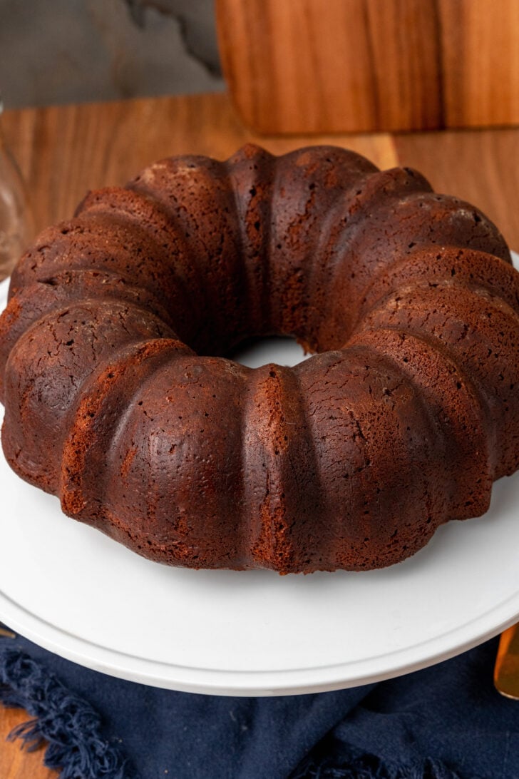 Southern chocolate pound cake on a white cake stand uncut.