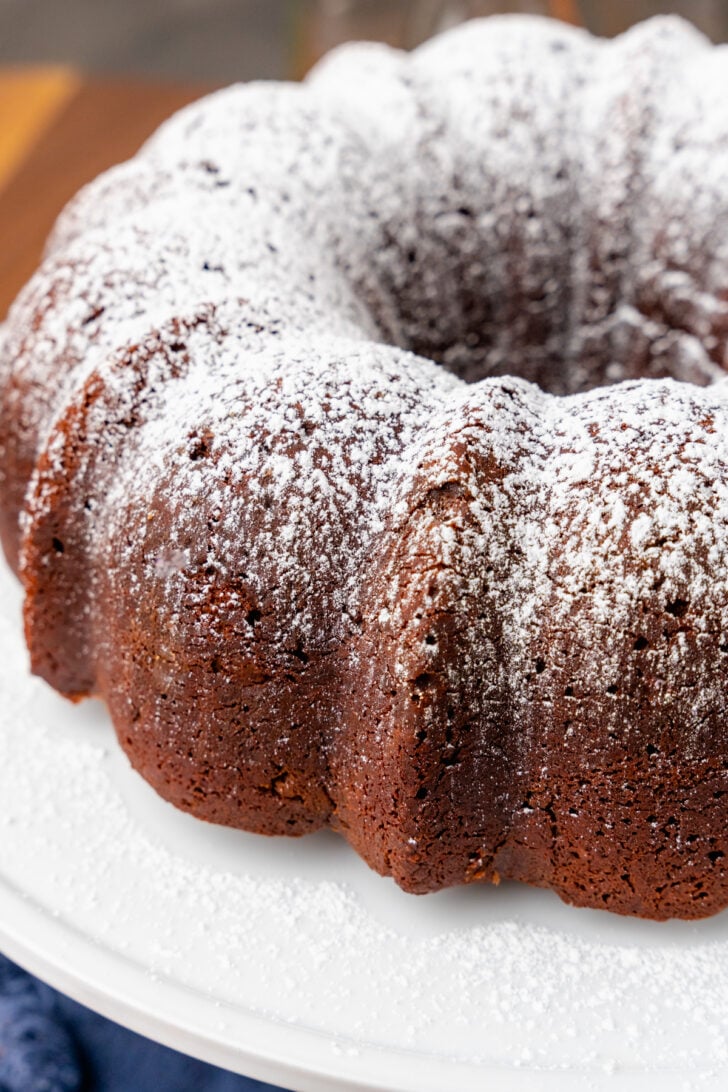 Southern chocolate pound cake on a white cake stand dusted with white powdered sugar.