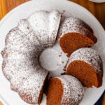Southern chocolate pound cake dusted with powdered cake with 3 slices on a white cake is amazingly delicious.