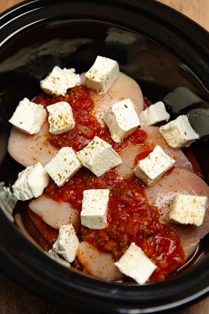 Crock Pot with chicken breasts, store bought salsa, cream cheese, and chipotle seasoning ready to be cooked.