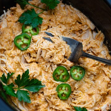 Crock Pot cooked chicken breasts cooked in salsa, cream cheese and seasoning the shredded and served with sliced jalapenose and fresh parsley.