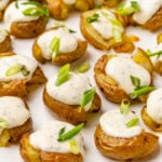 Crushed baby potatoes topped with homemade ranch dressing and chopped green onions served on a white platter