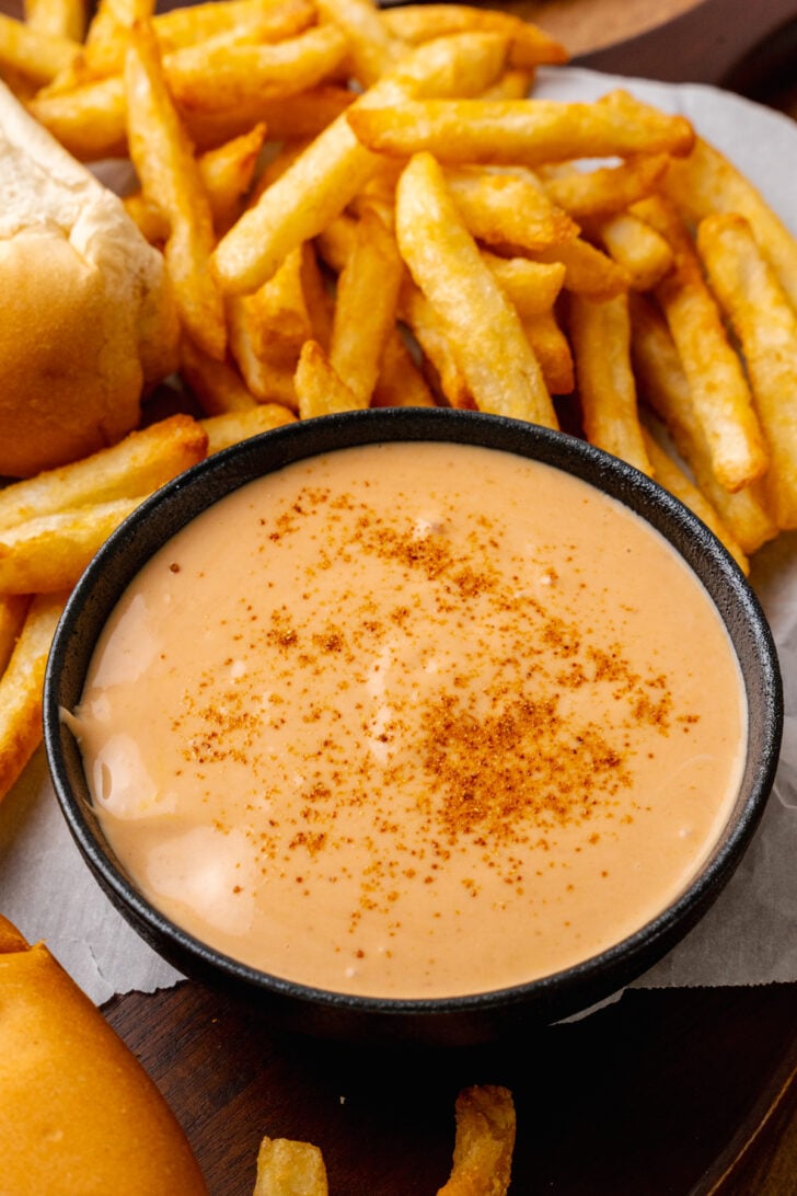 Fry sauce with a sprinkle of chili served in a black bowl with crispy french fries for a snack, lunch or dinner.