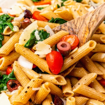 Whole wheat penne pasta tossed with fresh tomatoes, spinach, black olives in lemon juice and olive oil the topped with shaved Parmesan Cheese.