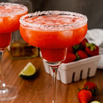 Sugar, salt rimmed glass rimmed glass with a fresh strawberry margarita with ice made with fresh fruit and limes.
