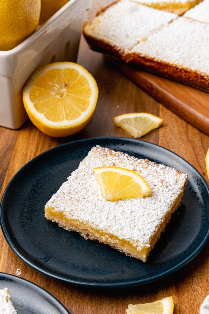 http://asouthern-soul.blogspot.com A lemon bar topped with a lemon slice served on a black plate for dessert.