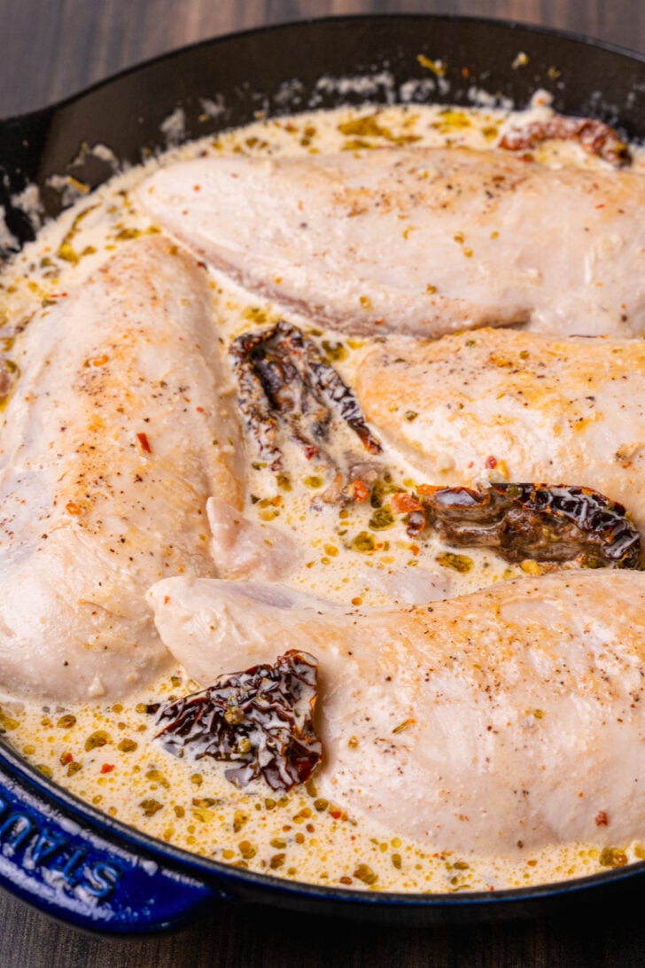 Chicken breasts cooked with sun dried tomatoes cooked in a light cream sauce with herbs and garlic in a skillet for Marry Me Chicken recipe.