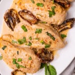 Marry Me Chicken made with chicken breasts, sun dried tomatoes, cooked in a light cream sauce with fresh basil served on a white plate.