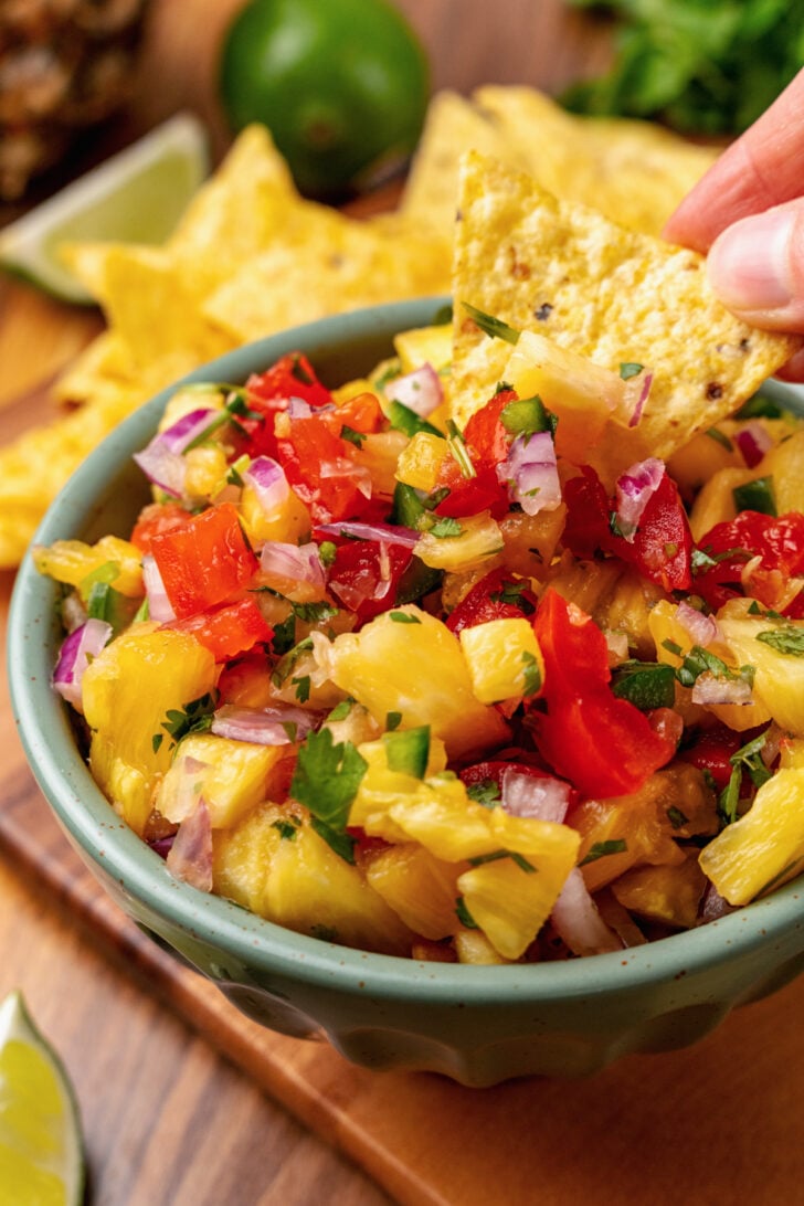 Chip being dipping into fresh pineapple dip with extra lime juice.