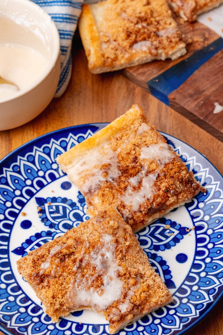 Two squares of cinnamon sugar pizza on a blue and white plate on a wooden table.