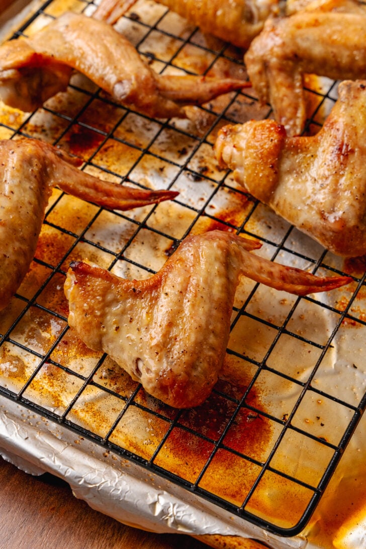 Chicken wings on a wire rack with a foil lined baking sheet.