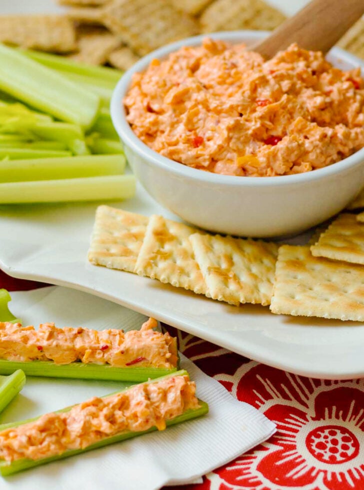 Homemade Pimento Cheese in a white bowl served with saltine crackers and celery sticks on a white platter.