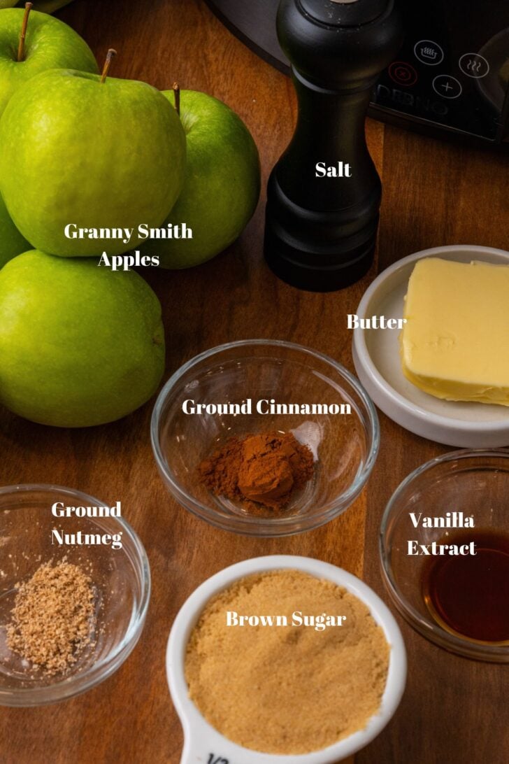 Chopped apple chunks with ground cinnamon and brown sugar in a black crock pot.