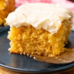 Slice of caramel snack cake with light, creamy caramel icing on a blue plate served with a silver fork.