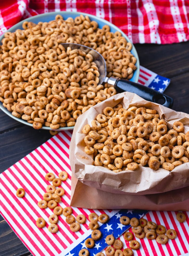 Fried cinnamon cheerios served in a brown paper bag and a bowl with a metal scoop.