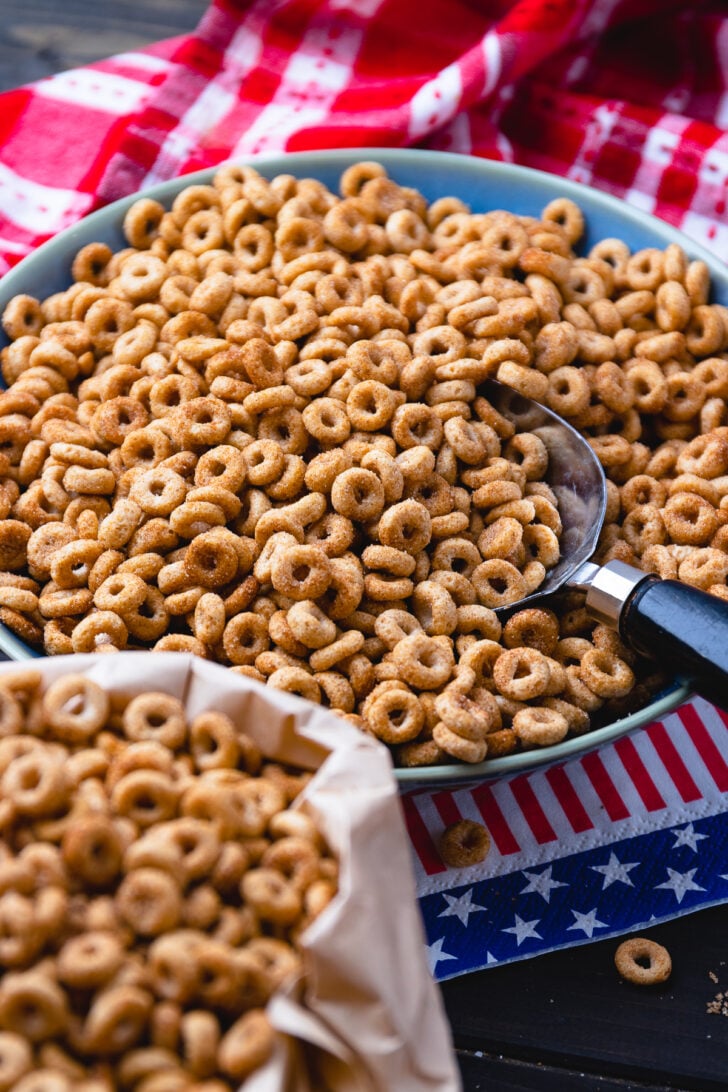 Fried cheerios, with butter and cinnamon served in a bowl with a scoop with black handle.