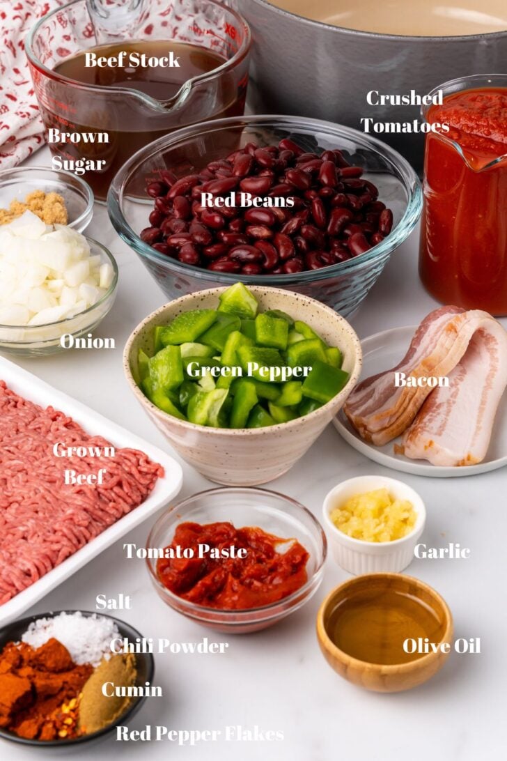 Ground beef, red beans, stock, green peppers, onion, crushed tomatoes, bacon and seasoning on a white counter for chili.