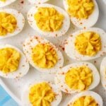 Stuffed deviled eggs on a white plate, sprinkled with paprika.
