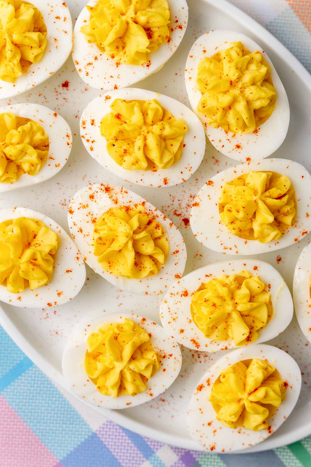 Stuffed deviled eggs on a white plate, sprinkled with paprika.