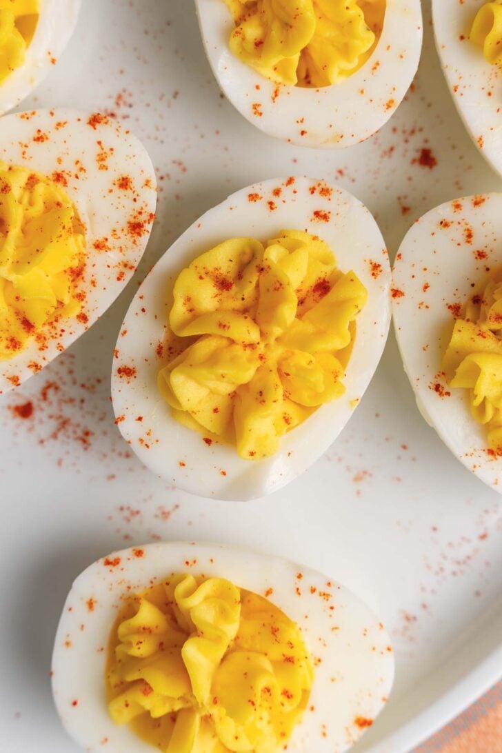 Stuffed deviled eggs on a white plate, sprinkled with paprika.