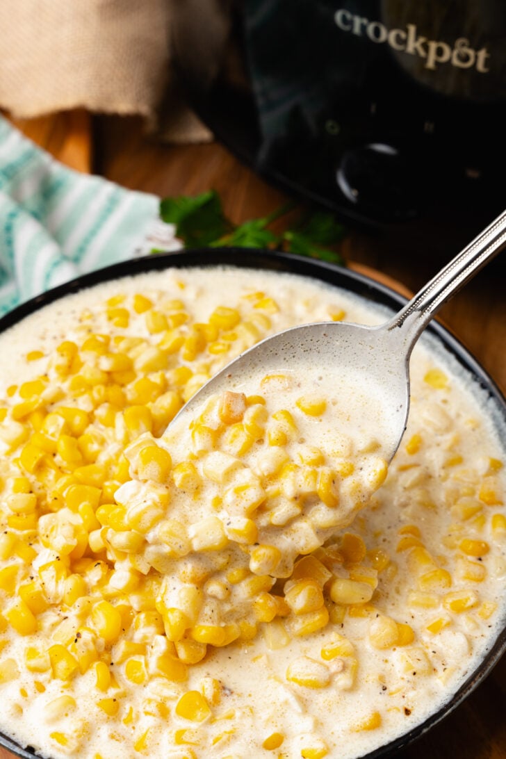Silver spoon with a scoop of creamed corn that has been cooked in the crock pot.