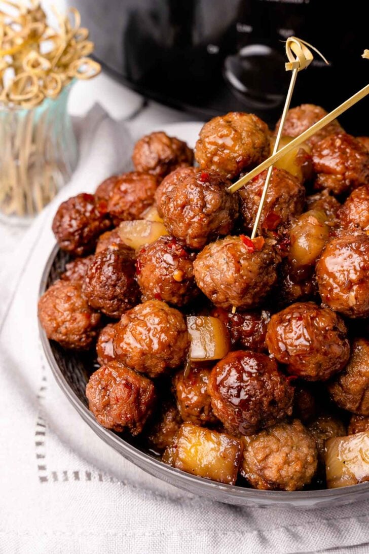 Cooked meatballs in sauce with pineapple chunks served with wooden skewers.