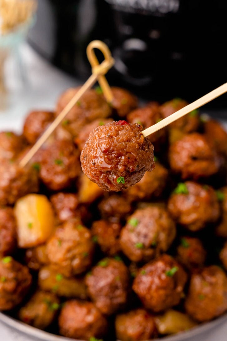 Cooked meatball on a wooden skewer.