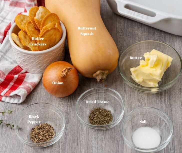 Butternut squash, butter crackers, whole onion, butter, black peppr, dried thyme and salt in glass container on a wooden counter.