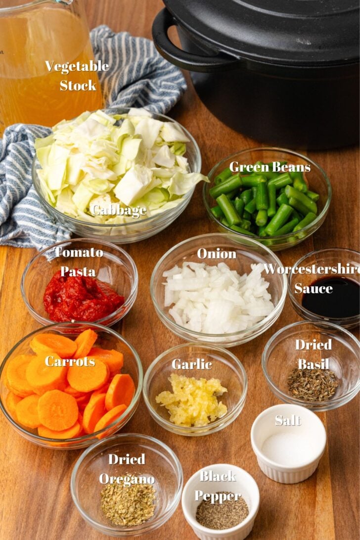 Clear glass bowls with chopped cabbage, green beans, chopped onions, tomato paste, worcestershire sauce, chopped carrots, garlic dried basil, dried oregano, salt and pepper.