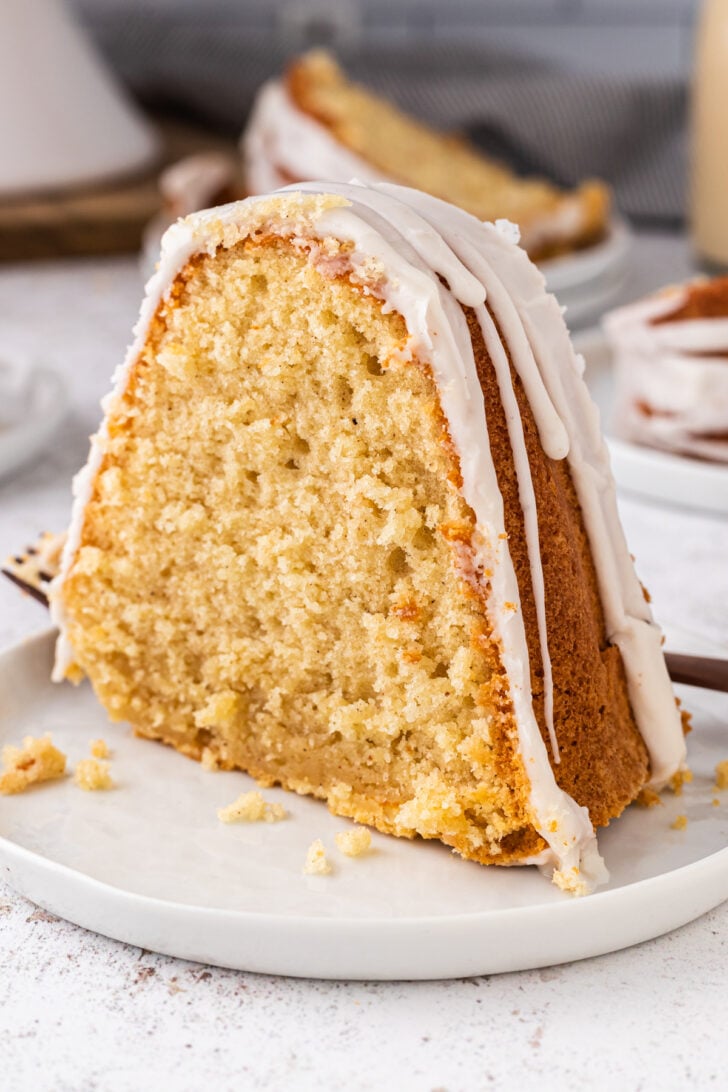 Slice of eggnog pound cake with white icing drizzle on a white desssert plate.