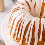 Eggnog pound cake with white icing drizzled, served on a white cake stand.