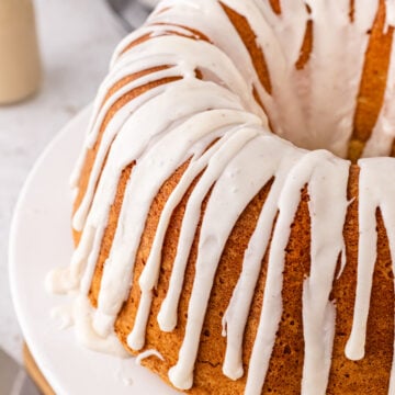 Eggnog pound cake with white icing drizzled, served on a white cake stand.