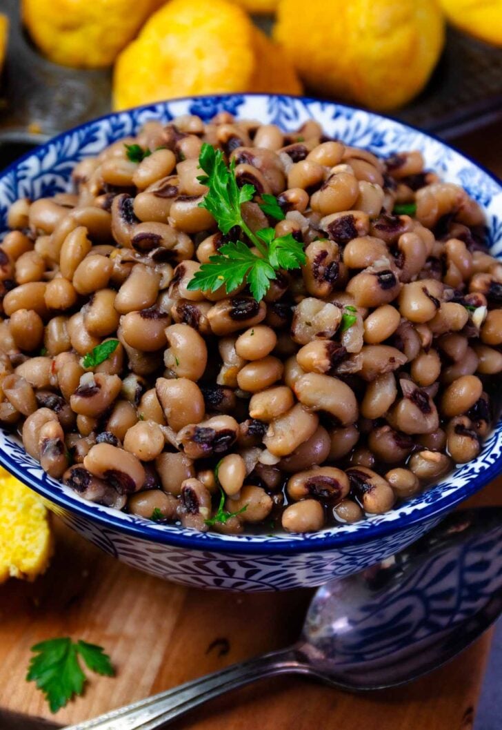 Black-eyed peas with black-eyed peas and red beans in blue and white bowl with parsley garnish, lemons in background IMG 0724