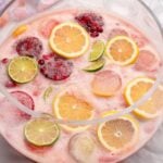 Glass punch bowl of punch with lemons, limes and fruit ice molds.