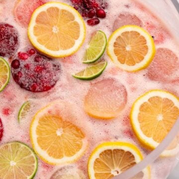 Glass punch bowl of punch with lemons, limes and fruit ice molds.