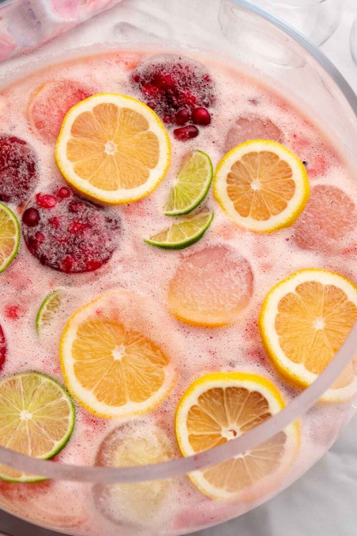 Glass punch bowl of punch with lemons, limes and fruit ice molds.