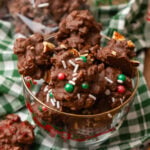 Chocolate pecan candy with green and red candy and white sprinkles and chopped pecans in a glass Christmas bowl.