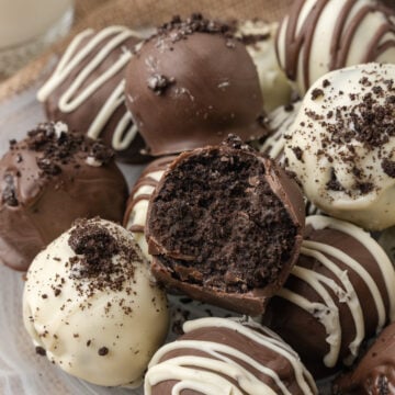 Oreo truffles with a bite out of it and a piping or white chocolate on top inside a basket.