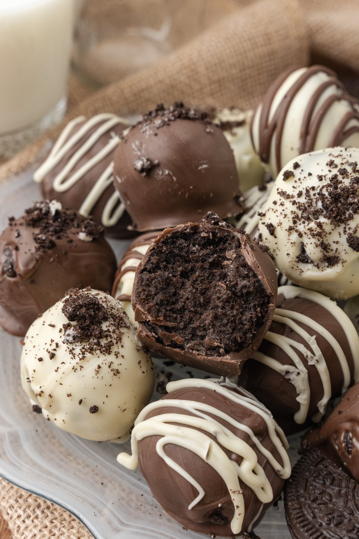 Oreo truffles with a bite out of it and a piping or white chocolate on top inside a basket.