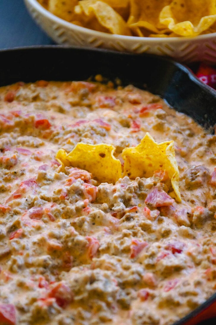 Chips sunk into a cast iron pan filled with creamy sausage dip.