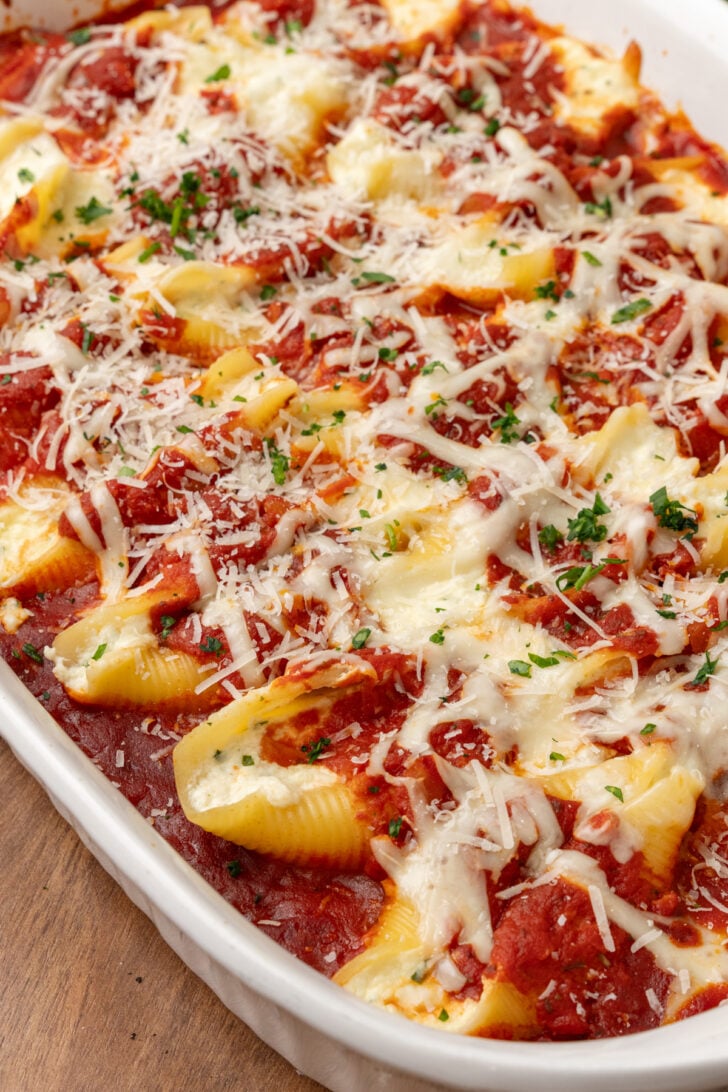 Baking dish filled with stuffed shells topped with cheese and marinara sauce.