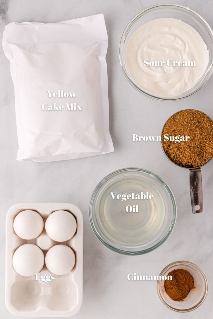 Ingredients for honey bun cake. Yellow cake mix, sour cream, brown sugar, vegetable oil, cinnamon, and eggs.