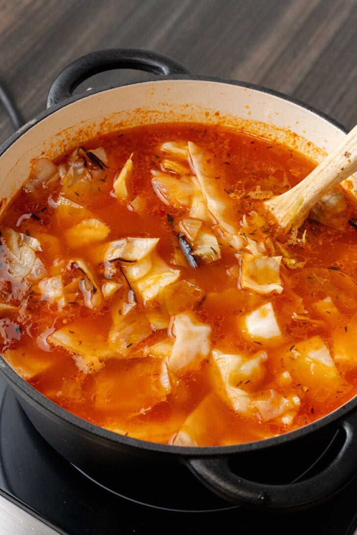 A black pot filled to the top with cozy cabbage soup.