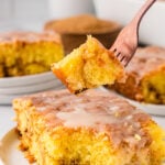 Honey bun cake on a white serving plate. With a chunk of it taken on with a fork ready to eat!