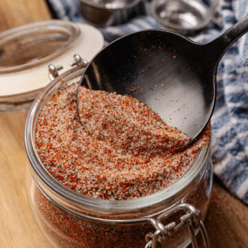 House seasoning blend in a small mason jar with a black spoon scooping some out.