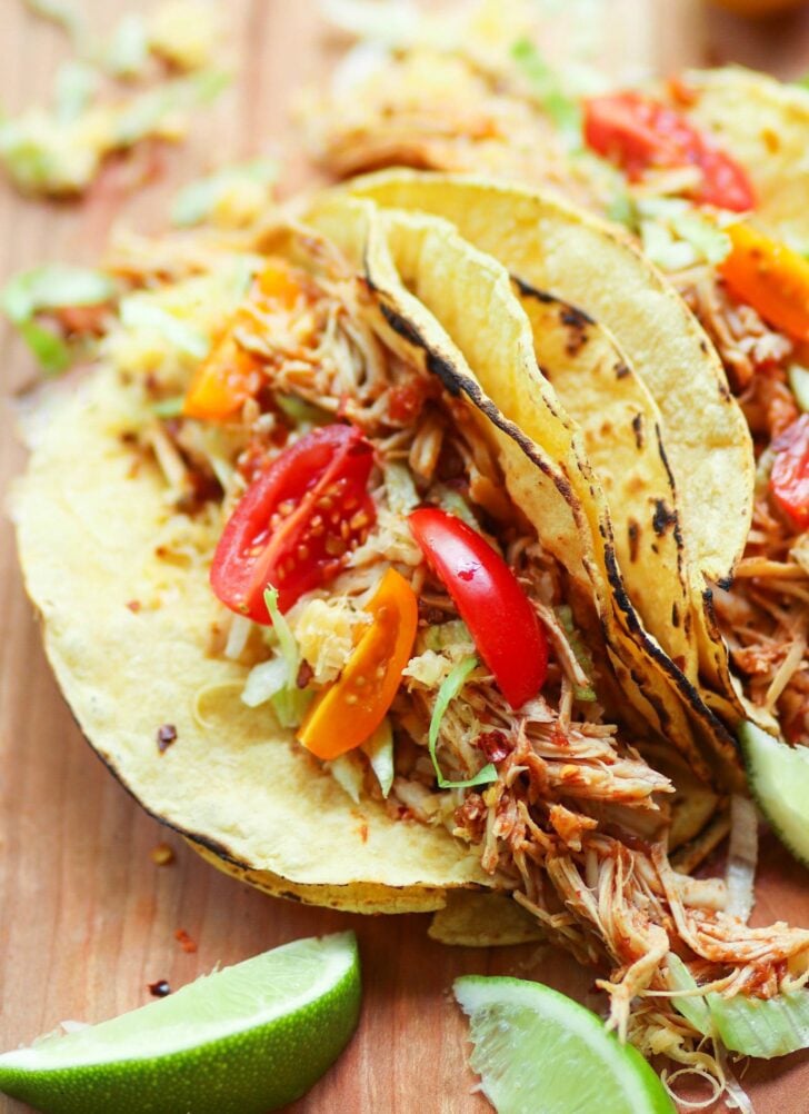 Crock pot salsa chicken stuffed in a tortilla topped with tomaotes and lettuce.