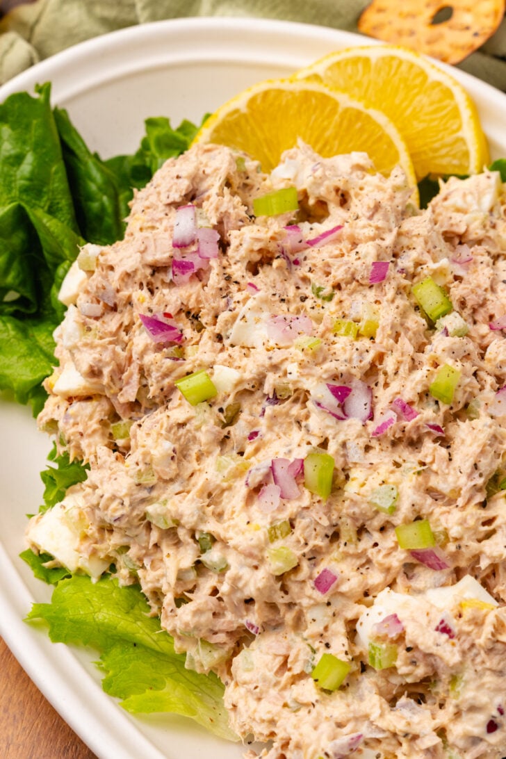 Tunsa salad placed on a green lead of lettuce sitting on a place with fresh lemon slices.