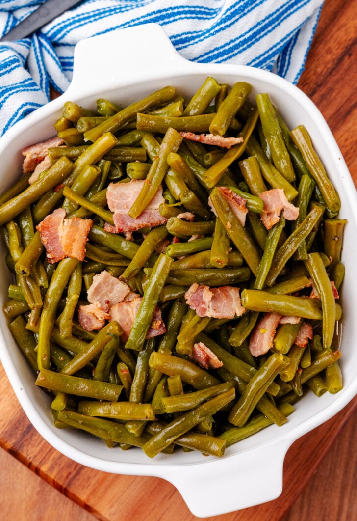 Cooked southern-style green beans in a white dish served for dinner.