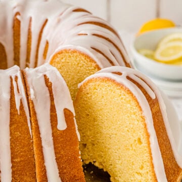 Slice of lemon pound cake being taken out with a nice drizzle of lemon icing on top of it.