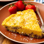 Perfectly cooked slice of a gluten free frittata on a plate with strawberries beside it.